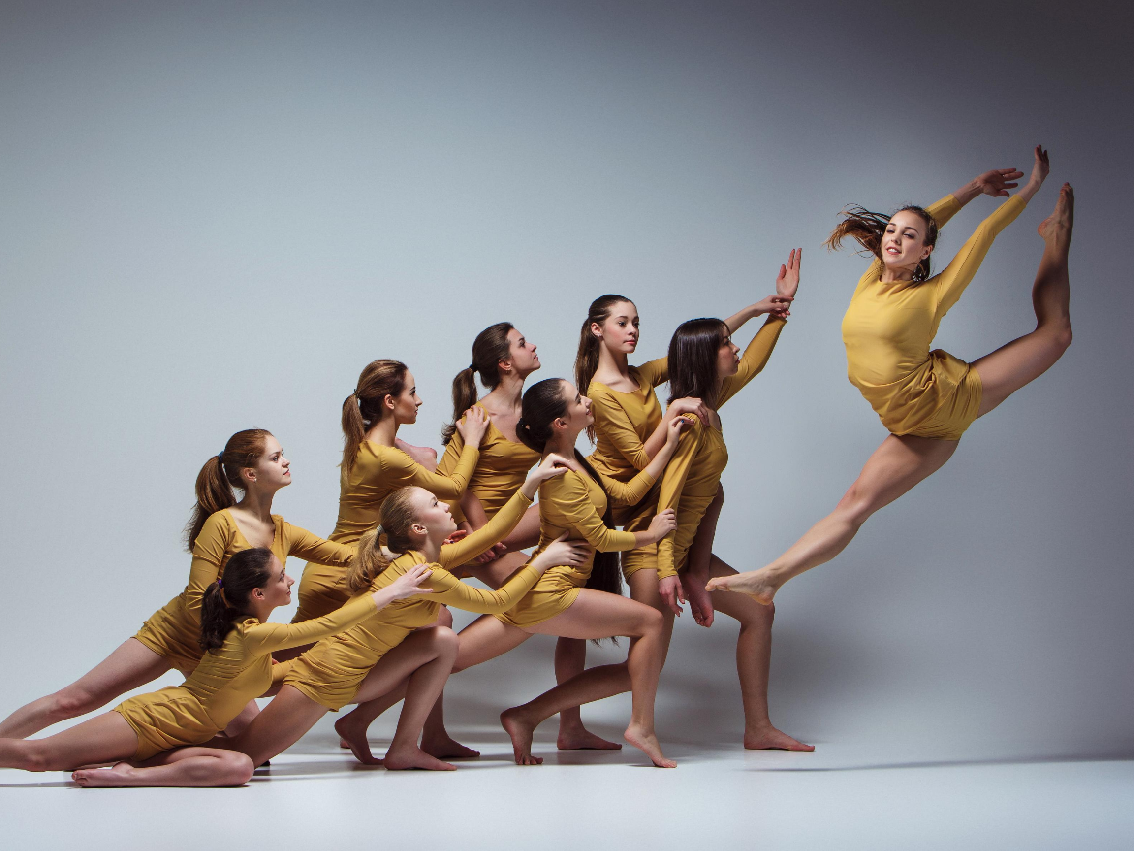 Picture of a group of dancers posing while one jumps in the air