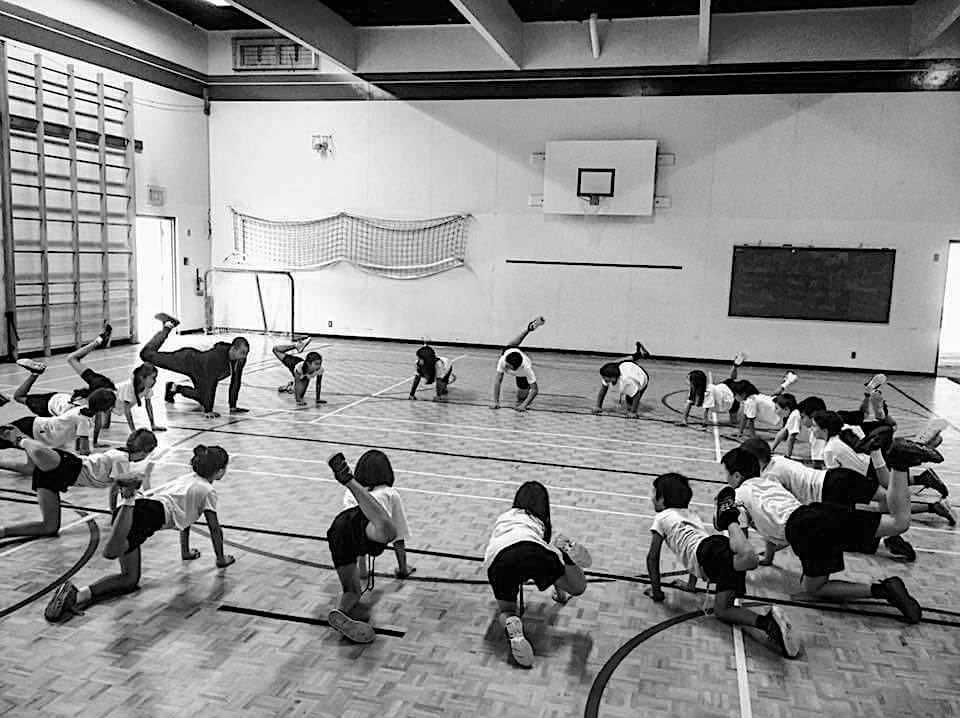 A group of kids in a circle, doing controlled articular rotations of the hips.